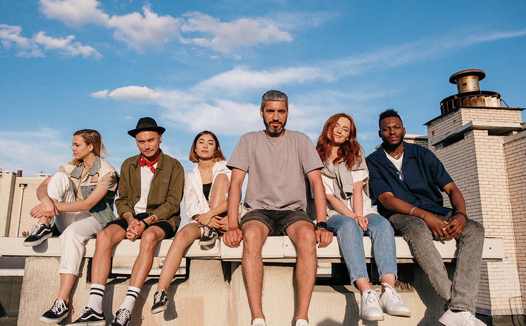 Group of people sitting together on a rooftop at sunset